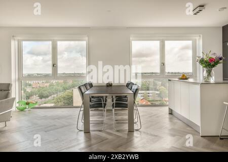 Ein heller und geräumiger, moderner Speisesaal mit großen Fenstern und Panoramablick auf die Stadt, elegantem Tisch und minimalistischer Einrichtung. Stockfoto