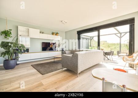Ein elegantes und modernes Wohnzimmer in der Duintopstraat mit sanften, natürlichen Farben, eleganten Möbeln und viel natürlichem Licht aus großem Glas Stockfoto