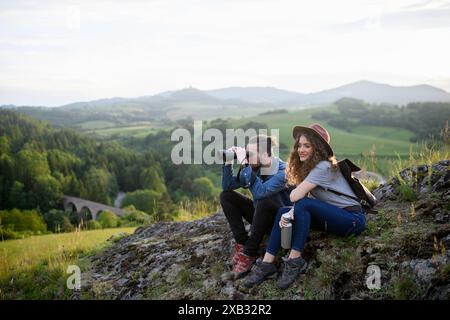 Reisende Paare wandern auf einem einfachen Wanderweg in der Natur mit Rucksäcken. Junge Touristen verbringen Sommerurlaub im Freien, sitzen auf Felsen und genießen Stockfoto