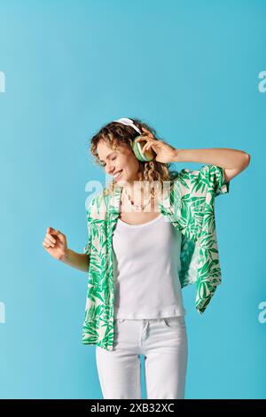 Stilvolle Frau in grünem Hemd und weißer Hose, die Musik hört. Stockfoto