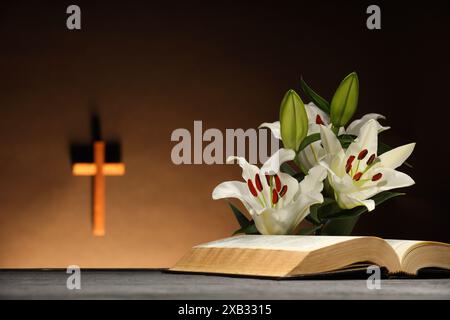 Bibel und Lilien auf grauem Tisch in der Kirche. Religion des Christentums Stockfoto