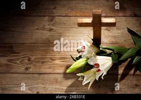 Kreuz und Lilien auf hölzernem Hintergrund, über der Ansicht mit Platz für Text. Religion des Christentums Stockfoto