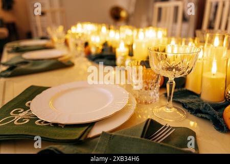 Ein gemütliches, stilvolles Wohnzimmer mit einem überdachten Tisch und einem dekorierten Weihnachtsbaum mit einer Girlande. Ein festliches Mittagessen oder eine Party. Beleuchtete Kerzen, Teller und Stockfoto