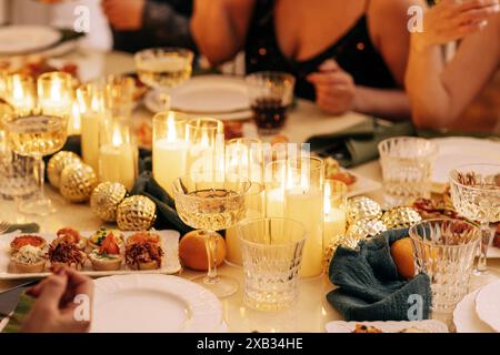 Ein überdachter festlicher Tisch mit Neujahrsdekor. Beleuchtete Kerzen, Snacks, Weihnachtskugeln, Teller und Gläser auf der Tischdecke. Eine Weihnachtsfeier. Ein fest Stockfoto