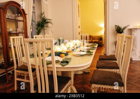 Ein Esstisch mit Kerzen und weihnachtlicher Einrichtung. Leeres Besteck. Warten auf die Gäste. Ein Neujahrsessen oder eine Party. Elegantes, elegantes Interieur von Stockfoto