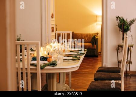 Ein Esstisch mit Kerzen und weihnachtlicher Einrichtung. Leeres Besteck. Warten auf die Gäste. Ein Neujahrsessen oder eine Party. Elegantes, elegantes Interieur von Stockfoto