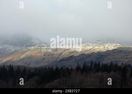 Sonnenlicht, das die schneebedeckten Fjäle von Loughrigg und Blea Rigg aus der Nähe von Waterhead Ambleside im Lake District England einfängt Stockfoto