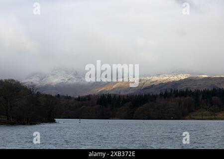 Sonnenlicht, das die schneebedeckten Fjäle von Loughrigg und Blea Rigg aus der Nähe von Waterhead Ambleside im Lake District England einfängt Stockfoto