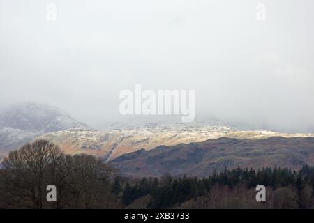 Sonnenlicht, das die schneebedeckten Fjäle von Loughrigg und Blea Rigg aus der Nähe von Waterhead Ambleside im Lake District England einfängt Stockfoto