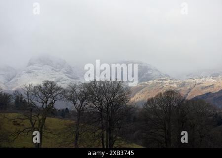 Sonnenlicht, das die schneebedeckten Fjäle von Loughrigg und Blea Rigg aus der Nähe von Waterhead Ambleside im Lake District England einfängt Stockfoto