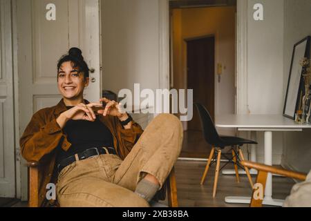 Porträt einer glücklichen jungen Frau, die zu Hause auf einem Stuhl sitzt Stockfoto