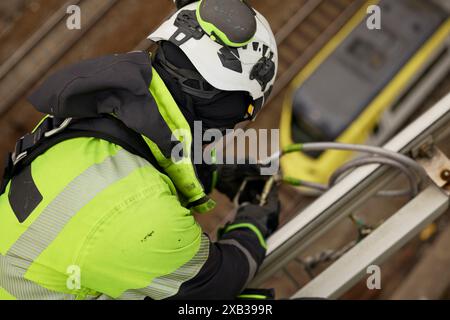 Hochwinkelansicht eines Arbeiters in Arbeitsschutzkleidung mit Karabiner auf Metall Stockfoto