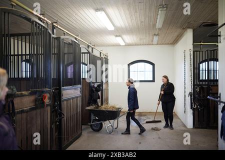 Mädchen und Bäuerin putzen den Stall zusammen Stockfoto