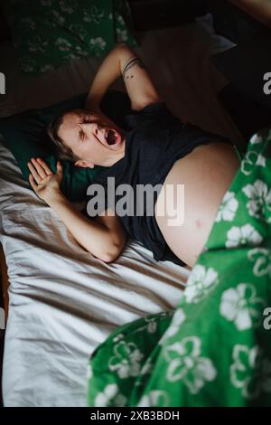 Hochwinkelansicht einer schwangeren Frau, die im Bett gähnt Stockfoto