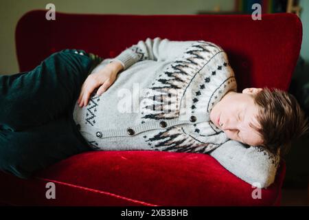Schwangere junge Frau, die zu Hause auf dem Sitz schläft Stockfoto