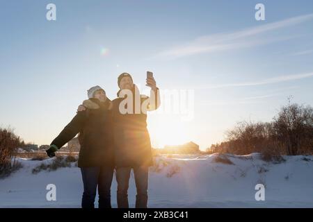 Mann, der Selfie mit Frau macht, während er im Winter auf Schnee steht Stockfoto