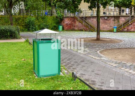 Mülltonne entlang eines einsamen Steinwegs in einem öffentlichen Park Stockfoto