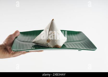 Nasi Lemak in Papier auf einem Teller gewickelt auf mittlerer Nahaufnahme Schuss von Hand Stockfoto