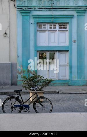 363 Bürgersteig-gelehntes Fahrrad neben einem großen Pflanzgefäß in der Calle Marti Street, Parque Agramonte Park, vor dem Casa Arte Jover House. Camaguey-Kuba. Stockfoto