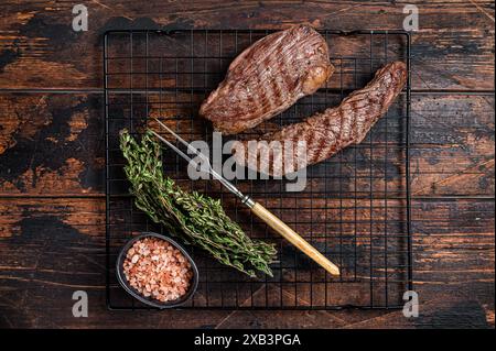 Gegrillte Sirloin Lap oder Bavette-Rindfleisch-Steak auf einem Grill mit Kräutern. Holzhintergrund. Draufsicht. Stockfoto