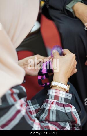 Eine Frau, die einen Hijab trägt, konzentriert sich darauf, Strümpfe mit Draht mit ihren Händen zu Formen und ist sehr vorsichtig Stockfoto