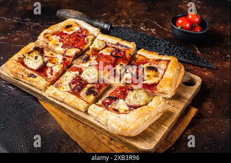 Vegetarische Blätterteigpizza mit Artischocke, Mozzarella, Tomaten und Käse auf einem Holzbrett. Dunkler Hintergrund. Draufsicht. Stockfoto