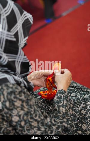 Eine Frau, die einen Hijab trägt, konzentriert sich darauf, Strümpfe mit Draht mit ihren Händen zu Formen und ist sehr vorsichtig Stockfoto