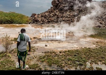 Ortskundiger Reiseleiter traditionell gekleidet und zeigt heiße geothermische vulkanische natürliche Quellen mit dampfendem Pool und kleinen bunten Seen, Geysiren und Bächen Stockfoto