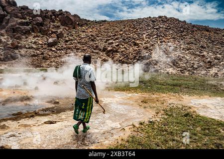 Ortskundiger Reiseleiter traditionell gekleidet und zeigt heiße geothermische vulkanische natürliche Quellen mit dampfendem Pool und kleinen bunten Seen, Geysiren und Bächen Stockfoto