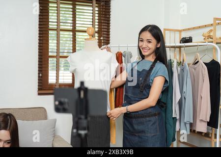 Junge Online-E-Business-Inhaber Livestreaming von Modeprodukten im Home Office, Präsentation von Kleidung auf Mannequin, Kundeninteraktion und Management Stockfoto
