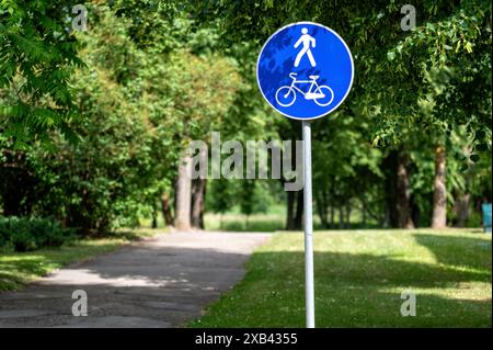 Ein blau-weißes Schild, das einen gemeinsamen Weg für Fußgänger und Radfahrer in einem Park anzeigt. Stockfoto