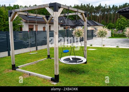 Ein moderner, quadratischer Holzspielplatz aus Metallecken, der auf dem Rasen im Hof steht. Stockfoto