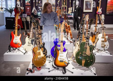 London, England, Großbritannien. Juni 2024. Bonhams-Mitarbeiter steht neben einer halbakustischen Gitarre des Gretsch Country Club, die auf 4.500 GBP - 5.000 GBP geschätzt wird (erste rechts), einer elektrischen Gitarre von Fender Stratocaster, die auf 25.000 GBP - 30.000 GBP (Mitte) geschätzt wird, und eine Gibson Les Paul Gold Top E-Gitarre, die auf 20.000 GBP - 000 GBP geschätzt wird, alle aus der Maxi Jazz-Kollektion von Faithless, ausgestellt im Bonhams Rock, Pop & Film Sale in Knightsbridge, London. (Kreditbild: © Thomas Krych/ZUMA Press Wire) NUR REDAKTIONELLE VERWENDUNG! Nicht für kommerzielle ZWECKE! Quelle: ZUMA Press, Inc./Alamy Live News Stockfoto