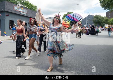 Ein animierter Marscher in der Poughkeepsie Pride Parade Holding 2024 und LGBTQ farbige Fan Plugging Deep Eddy Vodka. Stockfoto