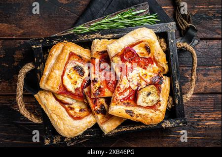 Blätterteig Tortenpizza mit Artischocke, Mozzarella, Tomaten und Käse in einem Holztablett. Holzhintergrund. Draufsicht. Stockfoto