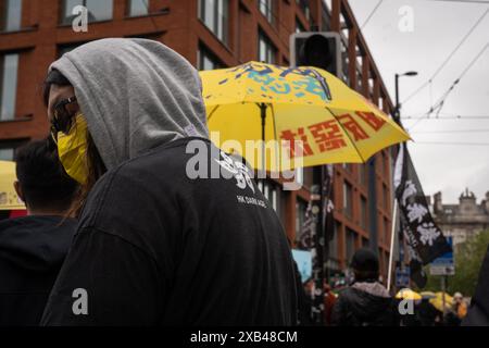 Ein Demonstrant, dessen Hemd "HK Dark Age" aufgedruckt hat, wurde zurückblickend gesehen, während Dutzende Demonstranten mit Fahnen, auf denen stand: "Befreien Sie Hongkong, Revolution unserer Zeit" und gelben Regenschirmen, die damals von der Bewegung wild benutzt wurden, in Manchester marschierten. Die Bevölkerung Hongkongs hielt vor fünf Jahren einen Protestmarsch im Stadtzentrum von Manchester ab, um der Demokratiebewegung in Hongkong zu gedenken, eine der größten Demonstrationen in der Geschichte Hongkongs. was später zu einer Verkrampfung der Polizei und vielen Festnahmen führte, was dazu führte, dass Zehntausende von Bürgern die Stadt verließen Stockfoto