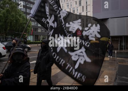 Manchester, Großbritannien. Juni 2024. Der Demonstrant trägt eine Flagge mit der Aufschrift "Befreien Sie Hongkong, Revolution unserer Zeit", die von der Bewegung damals wild benutzt wurde, die in Manchester marschierte. Die Bevölkerung Hongkongs hielt vor fünf Jahren einen Protestmarsch im Stadtzentrum von Manchester ab, um der Demokratiebewegung in Hongkong zu gedenken, eine der größten Demonstrationen in der Geschichte Hongkongs. was später dazu führte, dass sich die Polizei verkrampft und viele Festnahmen verhaftet wurden, was dazu führte, dass Zehntausende von Bürgern die Stadt verließen und nach Großbritannien, Taiwan und mehr zogen. Quelle: SOPA Images Limited/Alamy Live News Stockfoto