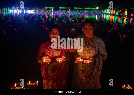 Zwei Frauen beleuchten Diwali-Lampen am Teich des Sri Sri-Baradeswari-Kalimata-Tempels in Basabo in Dhaka, Bangladesch. Stockfoto