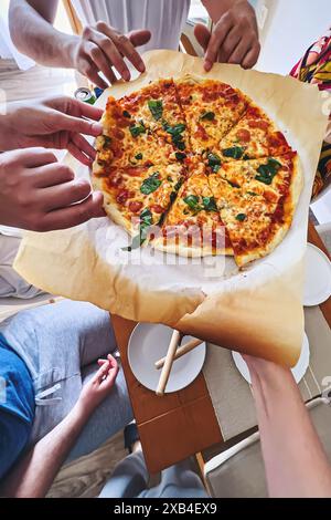 Gruppe von Freunden, die Pizzabschnitte schnappt, Nahaufnahme der Hände Stockfoto