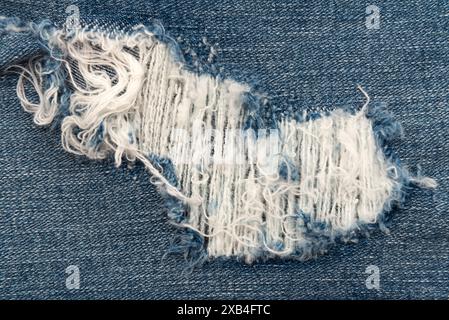 Nahaufnahme mit Loch in Jeans. Textur von verblasstem Denim Stockfoto