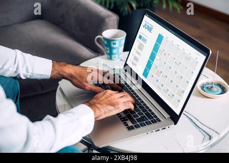 Mann, der mit einem digitalen Kalender auf einem Laptop arbeitet, früh am Morgen, um den Tag zu planen. Konzept des Online-Plans. Terminvereinbarung Für Besprechungen Buchen. Stockfoto