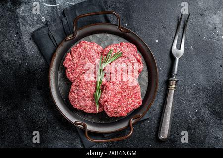 Ungekochte Frikadellen aus Hackfleisch, rohe Fleischschnitzel. Schwarzer Hintergrund. Draufsicht. Stockfoto