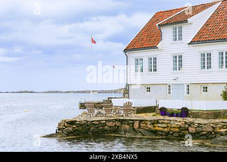 Traditionelle weiße Holzhäuser mit roten Ziegeldächern am Ufer im wunderschönen Fischerdorf Farsund, Norwegen Stockfoto