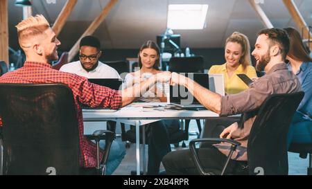 Teamzusammenarbeit in modernem Office Loft mit verschiedenen Kollegen, die während eines Tagessatzes eine Faustwelle teilen Stockfoto