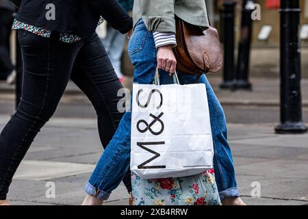 Weibliche Person, die mit einer Tragetasche von M&S Marks und Spencer unterwegs ist Stockfoto