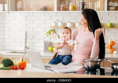 Mutter und Baby genießen den Morgen in der hellen modernen Küche Stockfoto