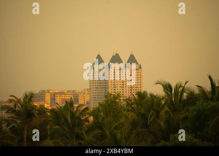 Ein atemberaubendes Dämmerungsfoto, das ein markantes Hochhaus mit dreieckigen Dächern vor dem Hintergrund eines goldfarbenen Himmels zeigt. Stockfoto