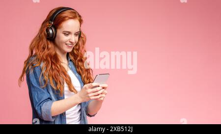 Frau, die Kopfhörer trägt und ihr Telefon ansieht Stockfoto
