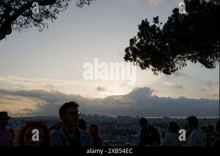 Die Menschen versammeln sich während der beliebten Heiligenfestlichkeiten in miradouro da graca, mit dem Blick auf den Sonnenuntergang der Stadt vor dem Abendhimmel Stockfoto