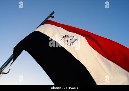 Ägyptische Flagge oder Flagge von Ägypten mit dem Adler des Saladin, der auf dem blauen Himmel fliegt Stockfoto